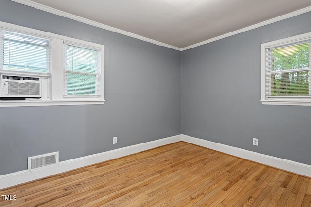 empty room with crown molding, plenty of natural light, cooling unit, and light hardwood / wood-style floors