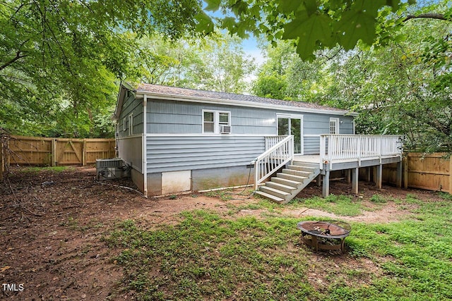 rear view of property with a wooden deck, a fire pit, and central AC