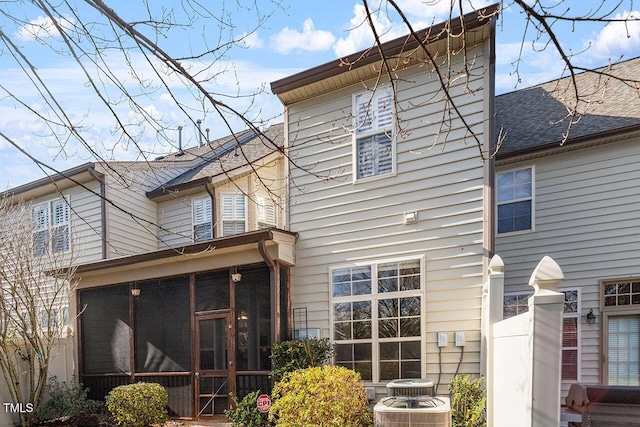 back of house with a sunroom, a shingled roof, and central AC unit