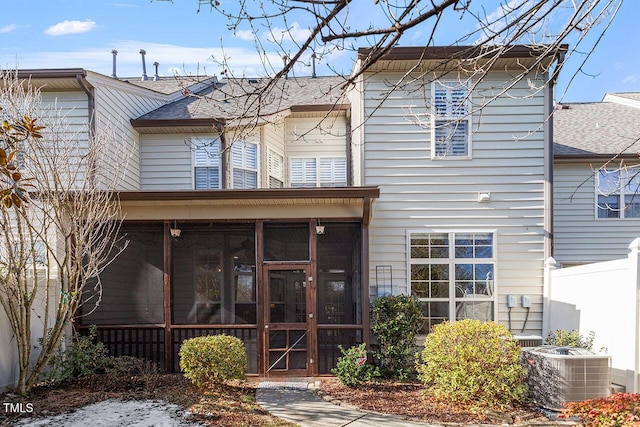 view of front of home with a shingled roof, cooling unit, and a sunroom