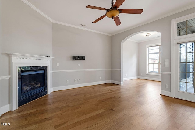 unfurnished living room featuring a fireplace, wood-type flooring, ceiling fan, and ornamental molding