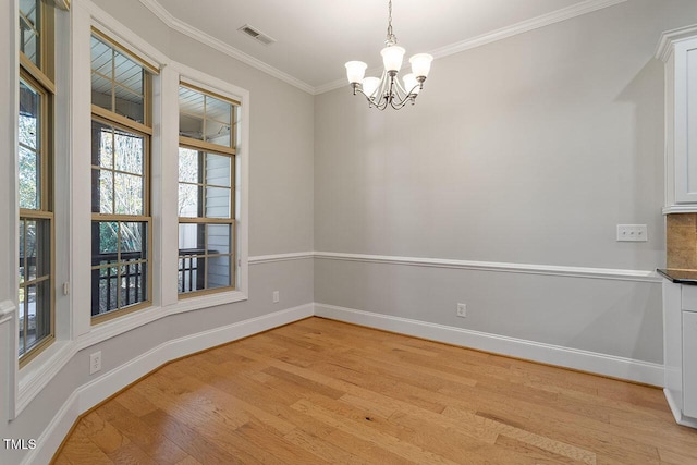 unfurnished dining area with baseboards, light wood finished floors, a chandelier, and crown molding