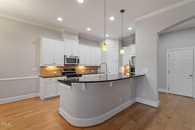 kitchen with decorative backsplash, light wood-type flooring, stainless steel appliances, decorative light fixtures, and white cabinets