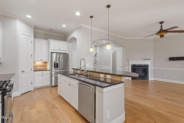 kitchen with sink, an island with sink, pendant lighting, white cabinets, and appliances with stainless steel finishes