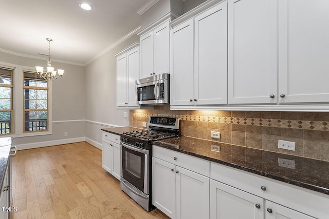 kitchen featuring white cabinetry, tasteful backsplash, dark stone countertops, a chandelier, and appliances with stainless steel finishes