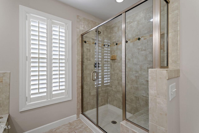 full bath with a shower stall, baseboards, and tile patterned flooring