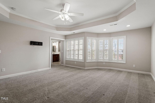 empty room with a tray ceiling, crown molding, carpet, and ceiling fan