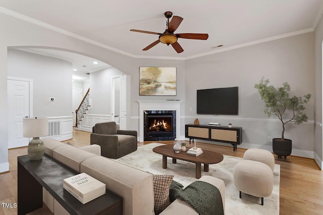 living room featuring visible vents, arched walkways, a premium fireplace, stairway, and light wood-type flooring