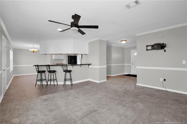 unfurnished living room featuring a textured ceiling, ceiling fan with notable chandelier, carpet floors, and crown molding