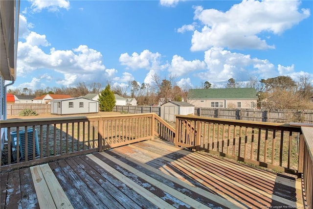 wooden terrace featuring a storage unit and a lawn