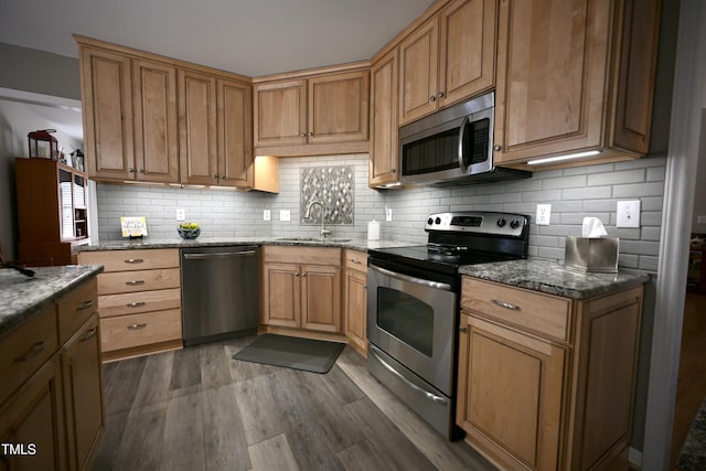 kitchen with sink, stainless steel appliances, stone countertops, and dark hardwood / wood-style floors