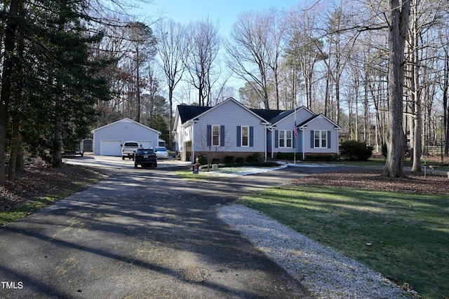 ranch-style house featuring a front lawn, a garage, and an outdoor structure