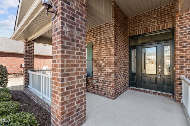 entrance to property featuring covered porch and brick siding