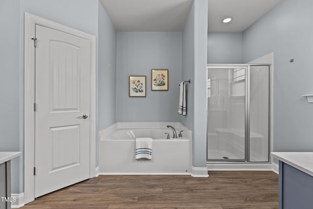 full bathroom featuring vanity, wood finished floors, a bath, and a shower stall