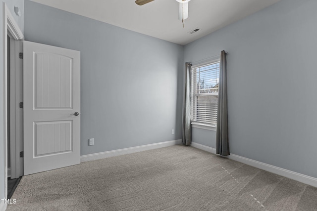 unfurnished room with a ceiling fan, visible vents, light carpet, and baseboards