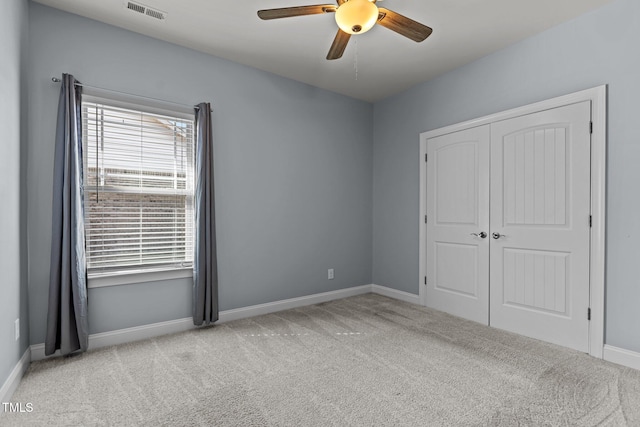 unfurnished bedroom featuring baseboards, visible vents, a ceiling fan, light colored carpet, and a closet