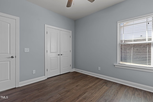 unfurnished bedroom featuring dark wood-type flooring, a closet, ceiling fan, and baseboards