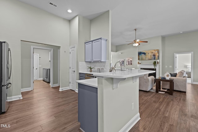 kitchen featuring a breakfast bar area, open floor plan, freestanding refrigerator, a peninsula, and light countertops