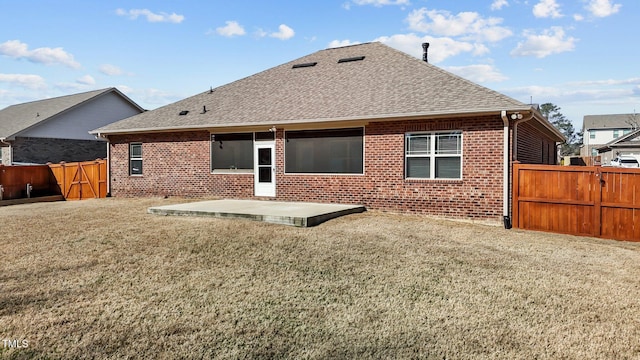 rear view of house featuring brick siding, roof with shingles, a patio area, and a fenced backyard