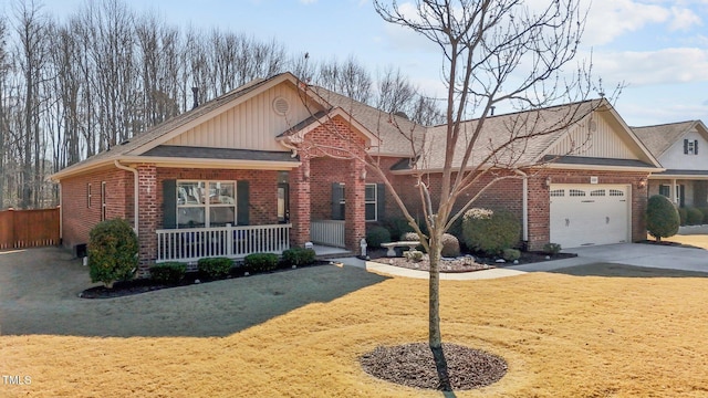 view of front of house featuring brick siding, covered porch, concrete driveway, a garage, and a front lawn