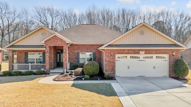 craftsman inspired home featuring brick siding, a shingled roof, covered porch, an attached garage, and driveway