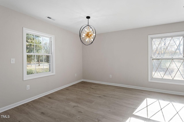 empty room with hardwood / wood-style floors and a chandelier