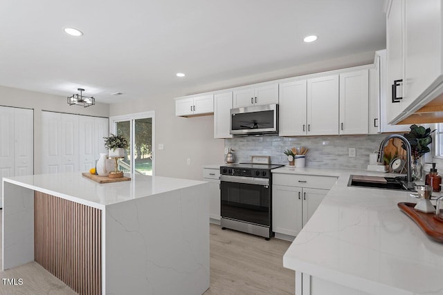 kitchen with white cabinets, light hardwood / wood-style floors, a center island, sink, and electric range oven