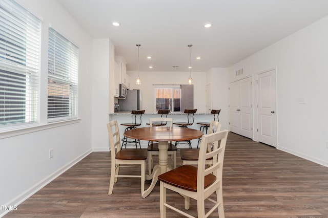 dining space featuring dark wood-type flooring, visible vents, and baseboards