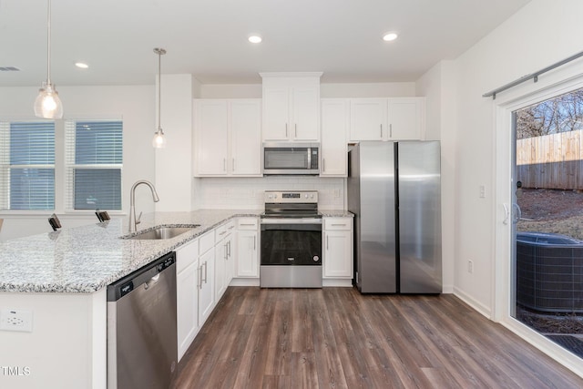 kitchen featuring white cabinetry, appliances with stainless steel finishes, a sink, and decorative light fixtures