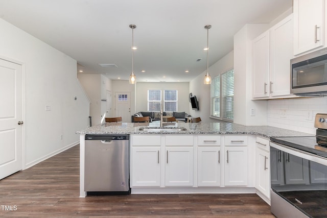 kitchen featuring a peninsula, a sink, white cabinetry, open floor plan, and appliances with stainless steel finishes