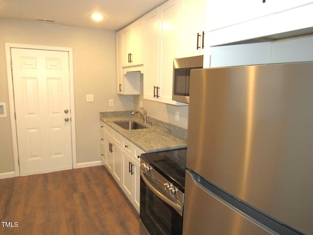 kitchen featuring appliances with stainless steel finishes, sink, white cabinets, light stone counters, and dark wood-type flooring