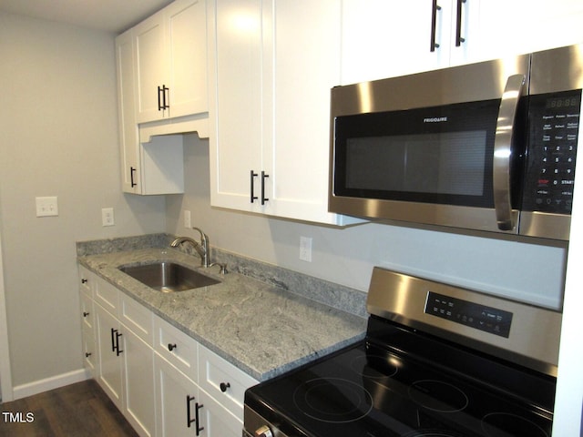 kitchen with sink, white cabinets, dark hardwood / wood-style flooring, light stone counters, and stainless steel appliances