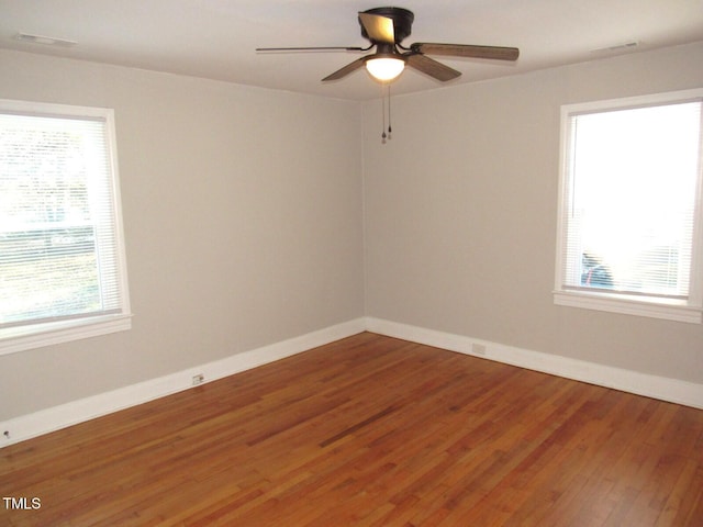 spare room featuring ceiling fan, a wealth of natural light, and wood-type flooring