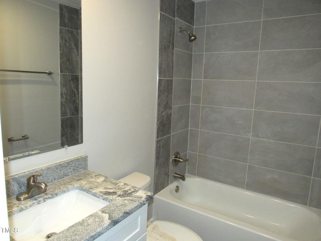 full bathroom featuring tiled shower / bath combo, vanity, and toilet