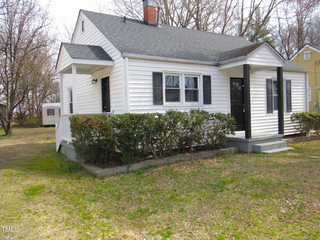 view of front of property featuring a chimney, a front lawn, and a shingled roof