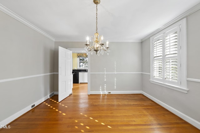 unfurnished dining area featuring crown molding, light wood-type flooring, and an inviting chandelier