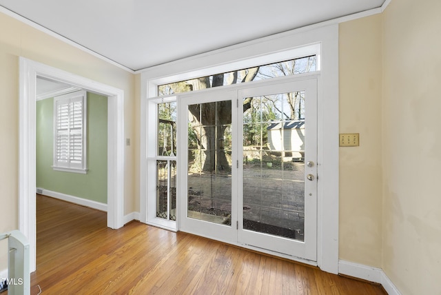 entryway featuring ornamental molding, a healthy amount of sunlight, and light hardwood / wood-style flooring