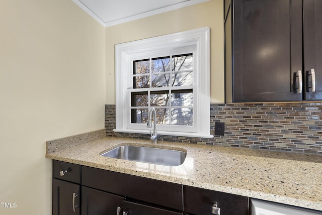 kitchen featuring dark brown cabinets, sink, backsplash, light stone counters, and ornamental molding