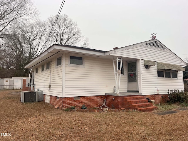 view of front of house with central AC and a front lawn