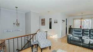 living room with ornamental molding, light wood-type flooring, and a notable chandelier