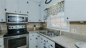 kitchen with appliances with stainless steel finishes, backsplash, and white cabinetry