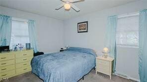 carpeted bedroom with multiple windows and ceiling fan