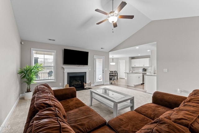 carpeted living room featuring high vaulted ceiling, sink, and ceiling fan