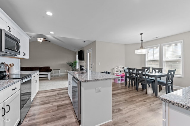 kitchen with white cabinetry, hanging light fixtures, a kitchen island with sink, light stone counters, and stainless steel appliances