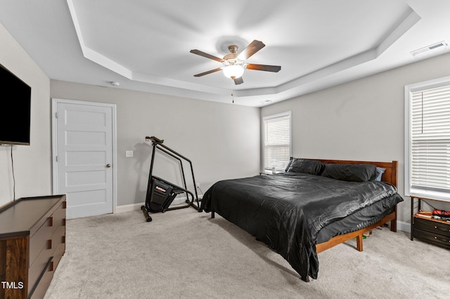 bedroom featuring a tray ceiling, light colored carpet, and ceiling fan