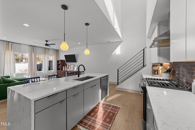 kitchen with sink, light stone counters, pendant lighting, stainless steel appliances, and decorative backsplash