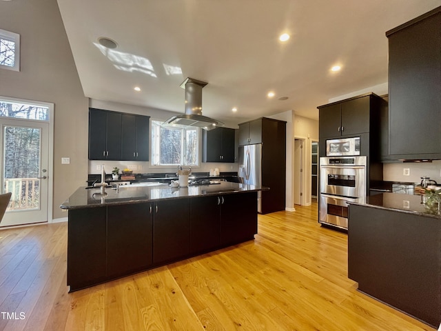 kitchen featuring stainless steel appliances, a kitchen island with sink, light hardwood / wood-style flooring, and island range hood