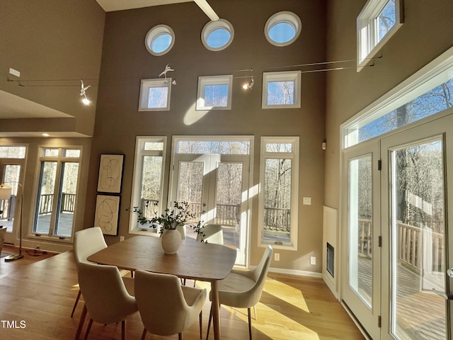 dining room with light hardwood / wood-style flooring, french doors, and a towering ceiling