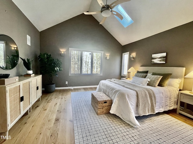 bedroom with ceiling fan, light hardwood / wood-style floors, and vaulted ceiling with skylight