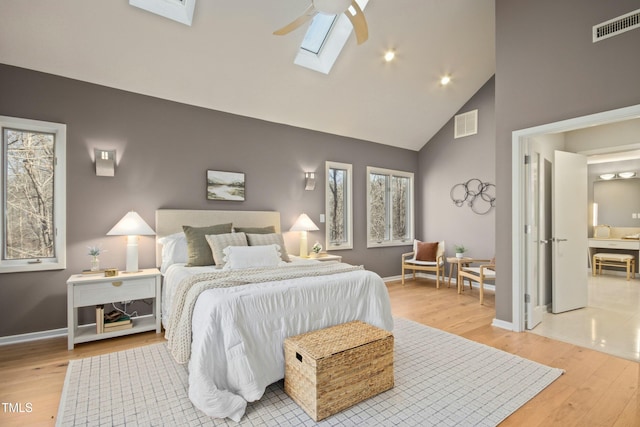 bedroom with light wood-type flooring, multiple windows, ceiling fan, and a skylight